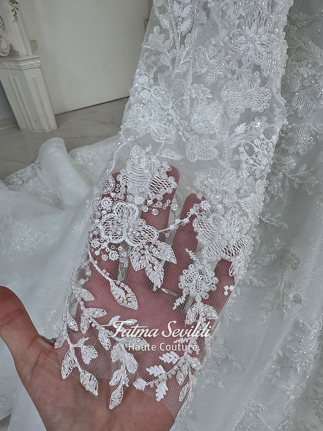Luxury white hijab wedding dress with long floral lace sleeves, a beaded princess skirt, illusion boat neckline, and a matching premium lace-edged veil.