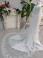 White mermaid satin-look hijab wedding dress with a high neckline, long sleeves, fitted bodice and floor-length train, styled with an intricate floral lace bridal veil. Fatma Sevildi Haute Couture modest bridal design.