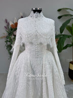 Off-white hijab wedding dress by Fatma Sevildi with beaded floral lace, a basque waist, long sleeves and a high neckline.