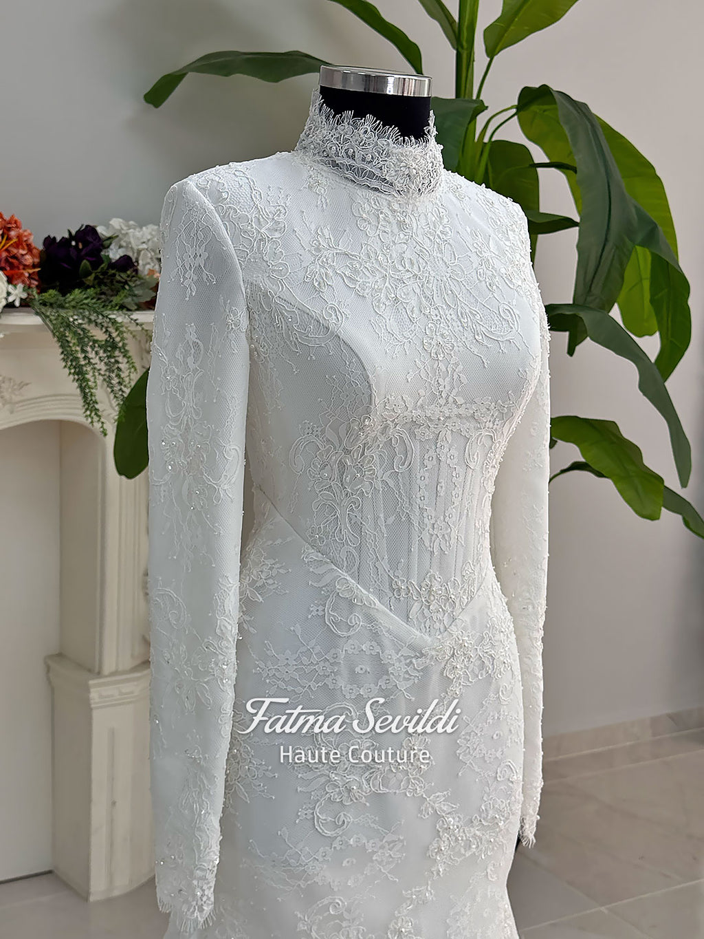 Luxury hijab wedding dress with mermaid silhouette and basque corset, featuring long sleeves, high neck lace, and a premium lace veil. Photographed on a mannequin in a bridal atelier setting.
