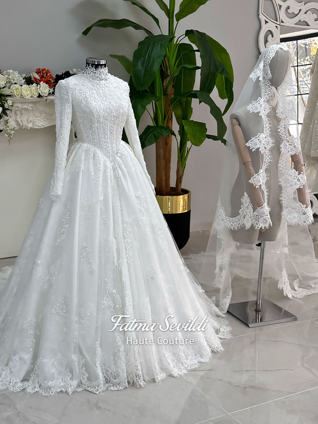 Luxury modest hijab wedding dress ball gown with long sleeves, high neck corset bodice, lace appliqué and included lace veil, photographed in a bridal atelier.