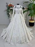 Ivory luxury hijab wedding dress featuring long lace sleeves, a high neckline, full beaded floral lace princess skirt, dramatic train and coordinating premium lace veil.