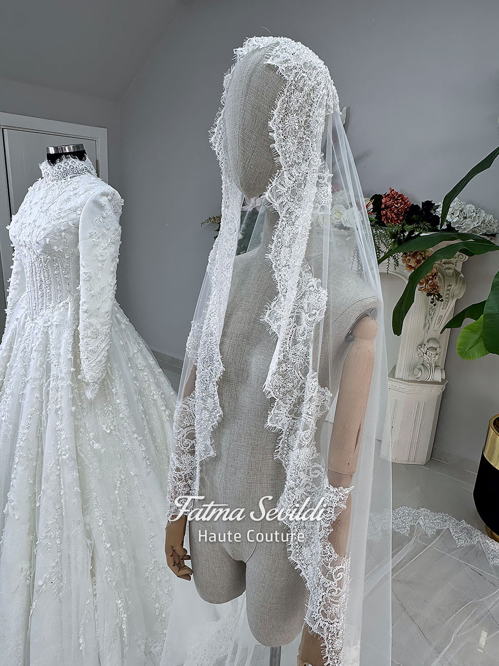White hijab wedding dress with long sleeves, high lace neckline, floral embroidery and a full modest bridal skirt, shown with a premium lace veil. Luxury Muslim wedding gown with detailed lace and elegant full coverage.