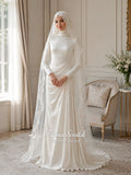 Luxury ivory hijab wedding dress with a high neckline, long sleeves, draped satin skirt and included premium lace veil displayed in a bridal atelier.