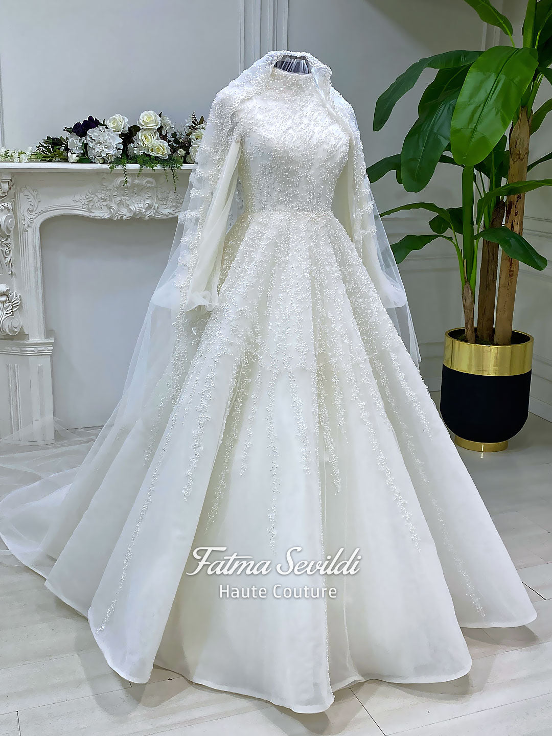 Luxury hijab wedding dress in an A-line tulle ball gown silhouette with long balloon sleeves, high neck, sparkling beadwork, and a lace-edged veil.