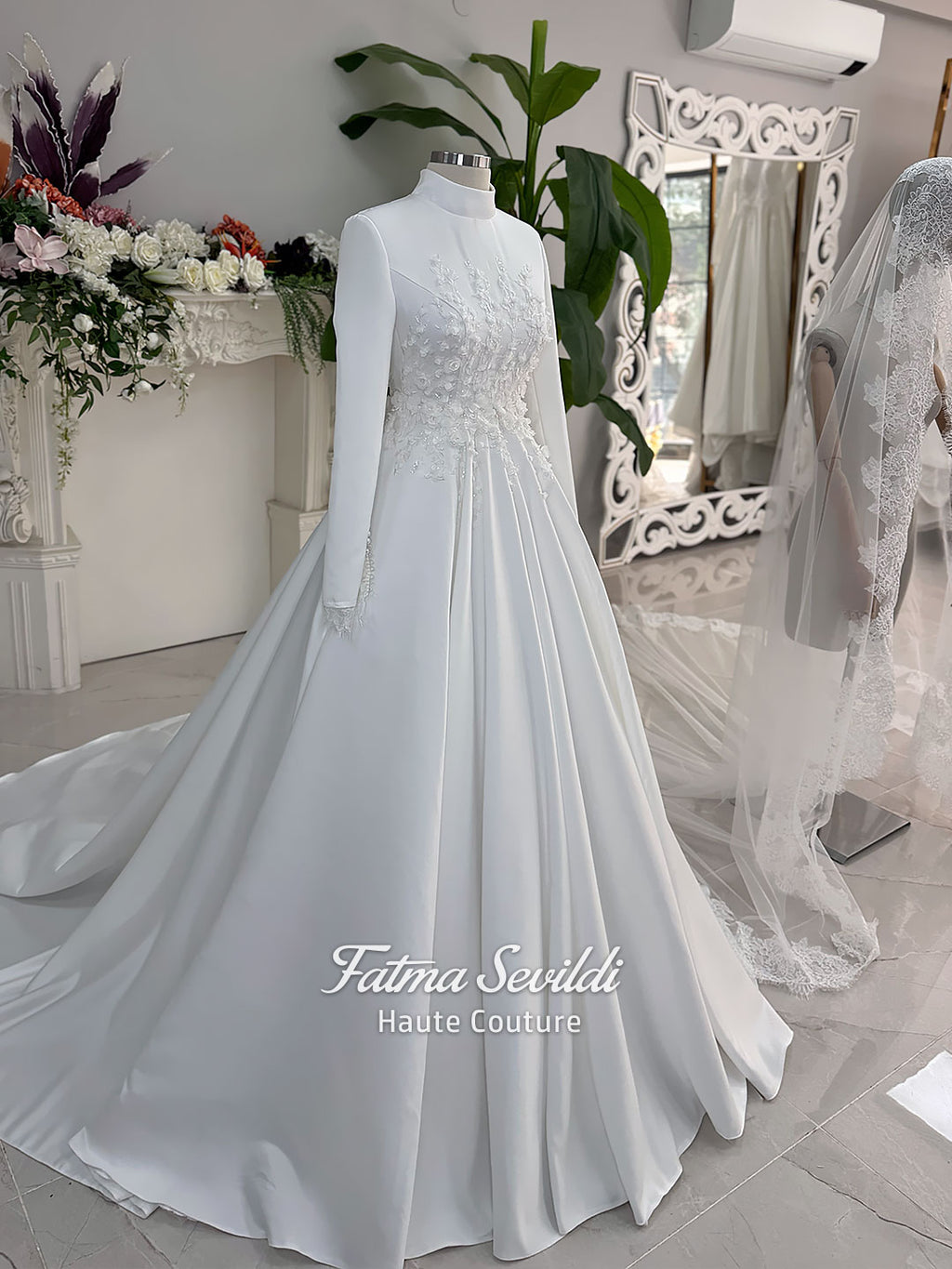 White A-line satin hijab wedding dress with long sleeves, high neckline, floral appliqué embroidery and an included premium lace mantilla veil for a modest Muslim bridal look.