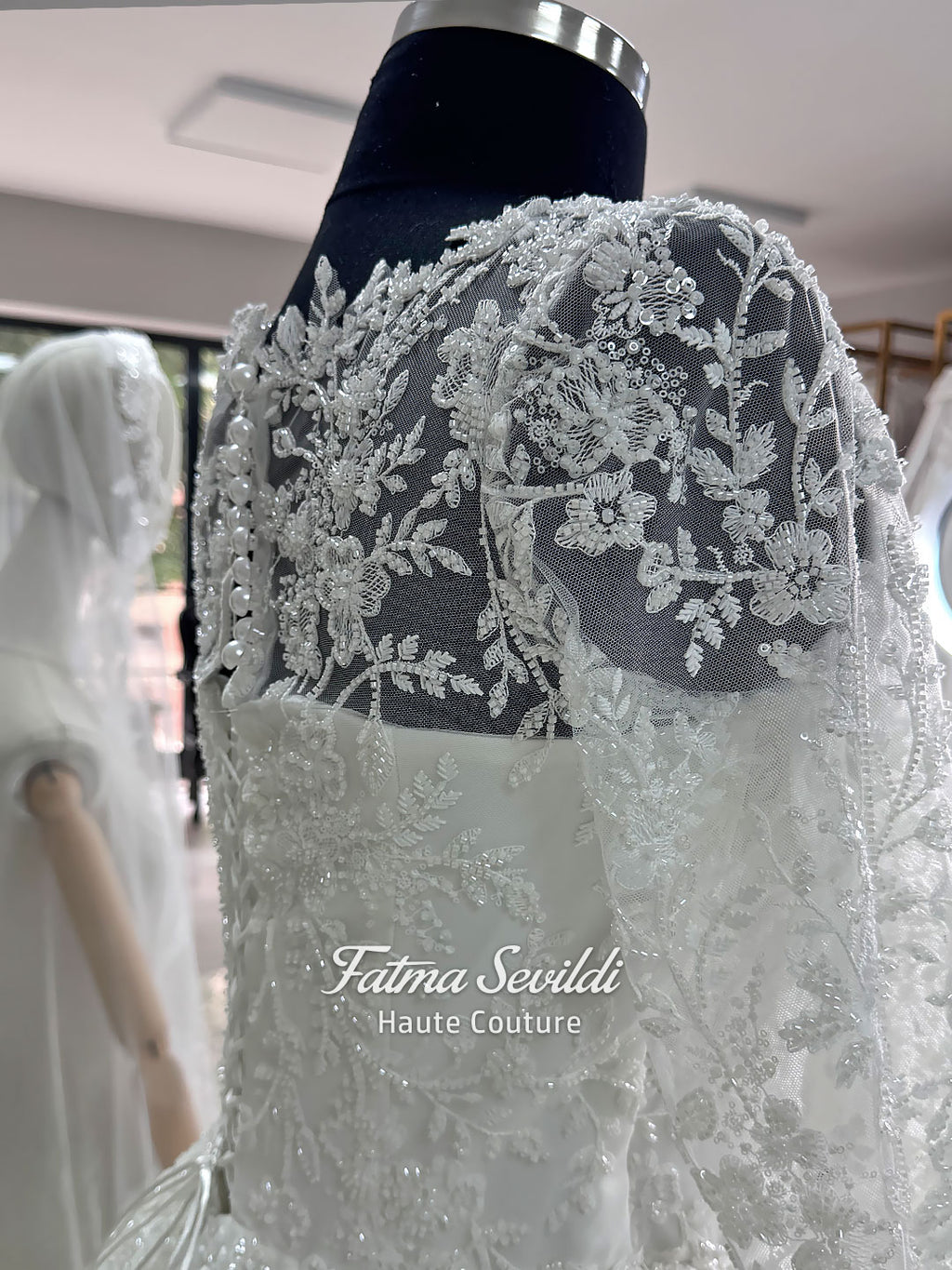 Luxury white hijab wedding dress with long floral lace sleeves, a beaded princess skirt, illusion boat neckline, and a matching premium lace-edged veil.