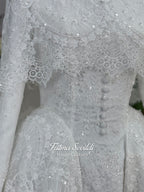 Off-white hijab wedding dress by Fatma Sevildi with beaded floral lace, a basque waist, long sleeves and a high neckline.