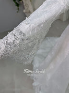 Off-white hijab wedding dress by Fatma Sevildi with beaded floral lace, a basque waist, long sleeves and a high neckline.