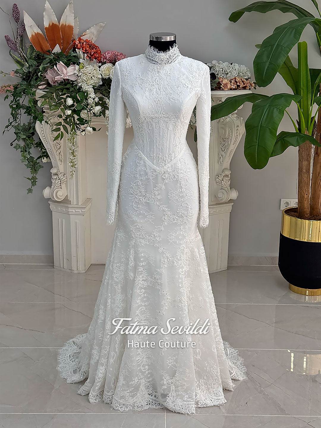 Luxury hijab wedding dress with mermaid silhouette and basque corset, featuring long sleeves, high neck lace, and a premium lace veil. Photographed on a mannequin in a bridal atelier setting.