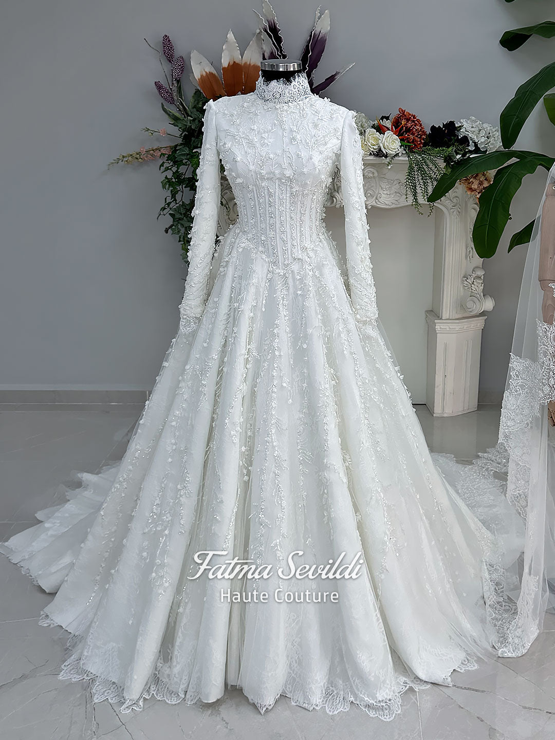 White hijab wedding dress with long sleeves, high lace neckline, floral embroidery and a full modest bridal skirt, shown with a premium lace veil. Luxury Muslim wedding gown with detailed lace and elegant full coverage.