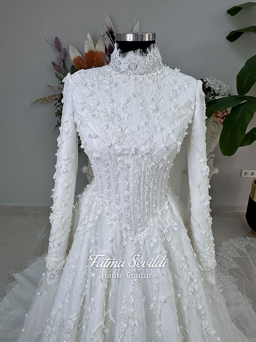 White hijab wedding dress with long sleeves, high lace neckline, floral embroidery and a full modest bridal skirt, shown with a premium lace veil. Luxury Muslim wedding gown with detailed lace and elegant full coverage.