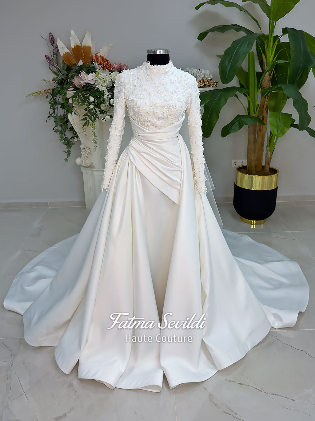 Luxury modest hijab wedding dress with long sleeves, 3D floral beaded lace bodice, draped satin A-line skirt and lace-edged veil included, shown on mannequin. Custom made Islamic bridal gown with elegant full coverage.