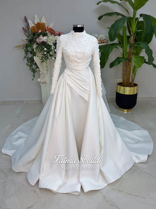 Luxury modest hijab wedding dress with long sleeves, 3D floral beaded lace bodice, draped satin A-line skirt and lace-edged veil included, shown on mannequin. Custom made Islamic bridal gown with elegant full coverage.