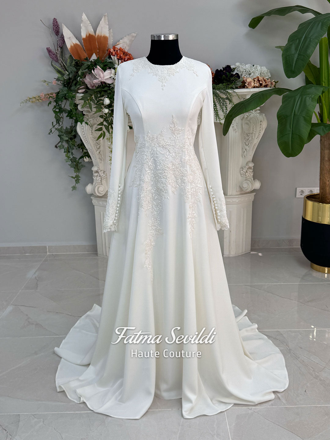 Ivory long sleeve hijab wedding dress with detachable lace-edged cape, floral beaded embroidery, high neckline and floor-length A-line modest bridal silhouette. Designed for Muslim brides seeking an elegant luxury wedding gown with full coverage.