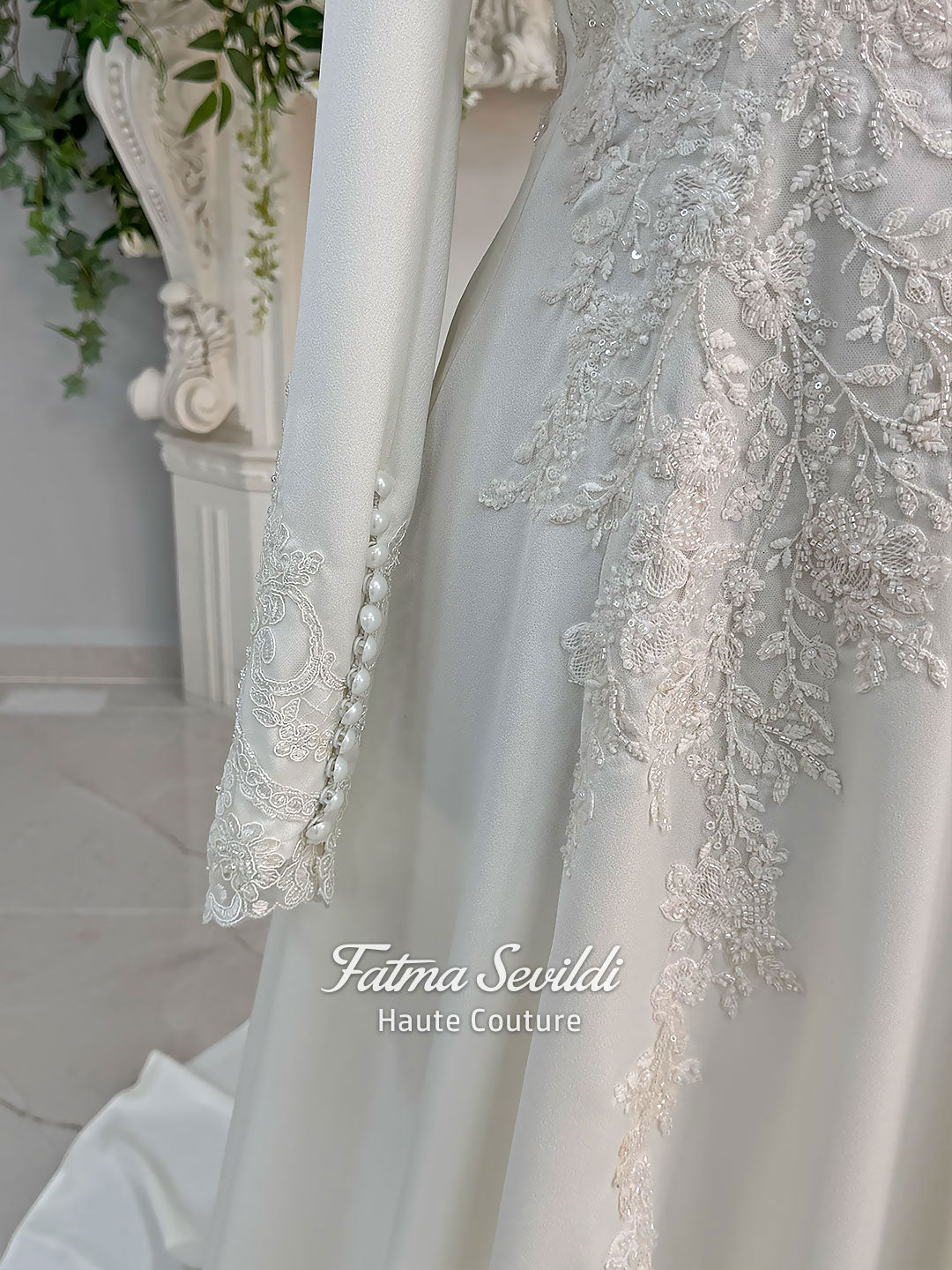 Ivory long sleeve hijab wedding dress with detachable lace-edged cape, floral beaded embroidery, high neckline and floor-length A-line modest bridal silhouette. Designed for Muslim brides seeking an elegant luxury wedding gown with full coverage.