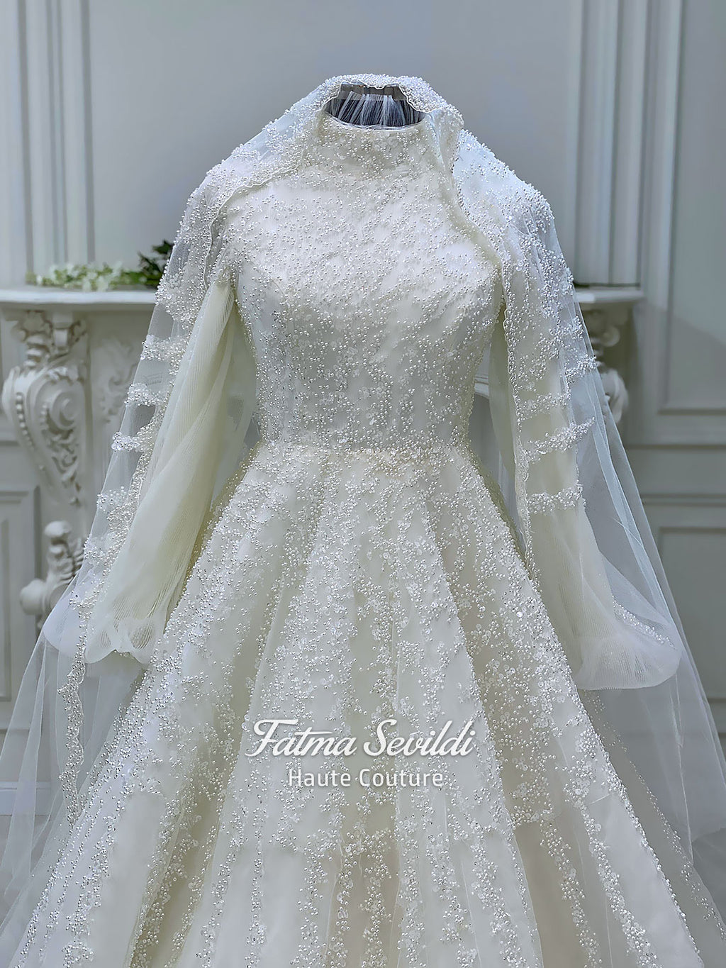 Luxury hijab wedding dress in an A-line tulle ball gown silhouette with long balloon sleeves, high neck, sparkling beadwork, and a lace-edged veil.