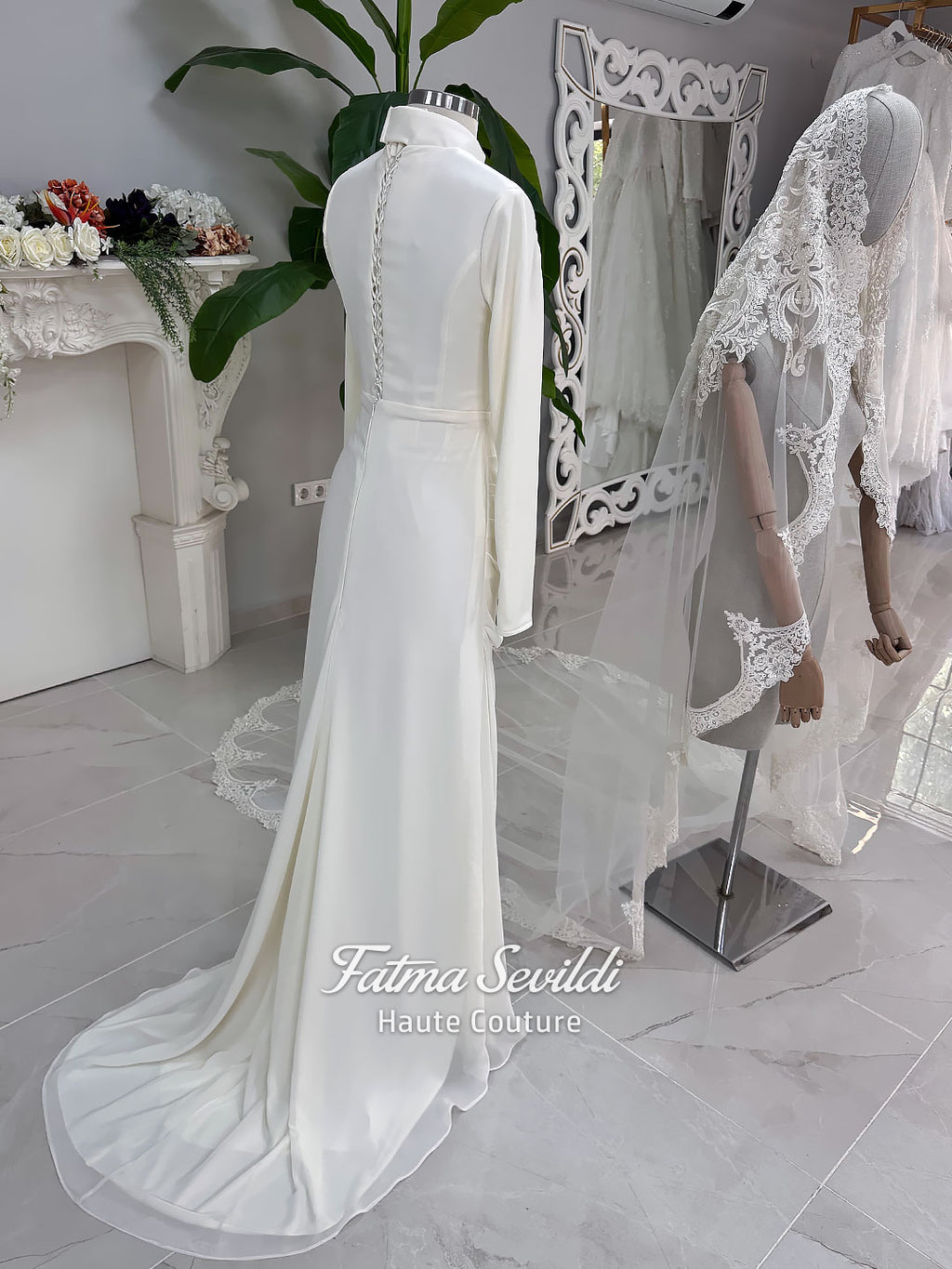 Luxury ivory hijab wedding dress with a high neckline, long sleeves, draped satin skirt and included premium lace veil displayed in a bridal atelier.