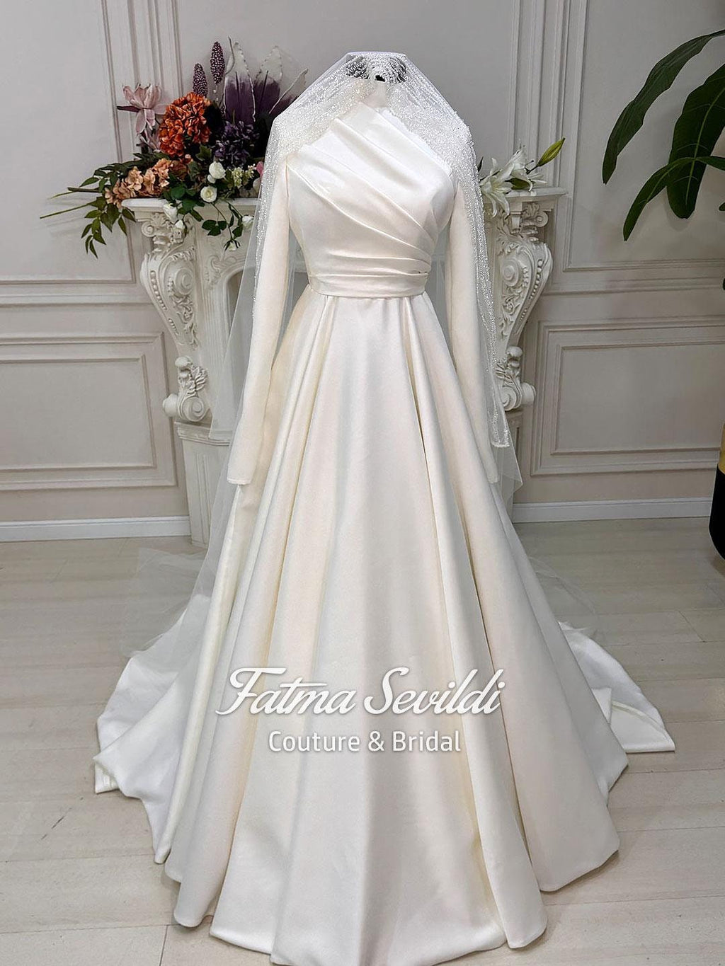 Elegant ivory satin Muslim wedding gown with high neck, long sleeves, draped bodice, fitted waist, flowing skirt, and lace veil