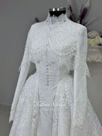 Off-white hijab wedding dress by Fatma Sevildi with beaded floral lace, a basque waist, long sleeves and a high neckline.