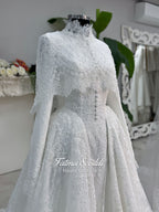 Off-white hijab wedding dress by Fatma Sevildi with beaded floral lace, a basque waist, long sleeves and a high neckline.
