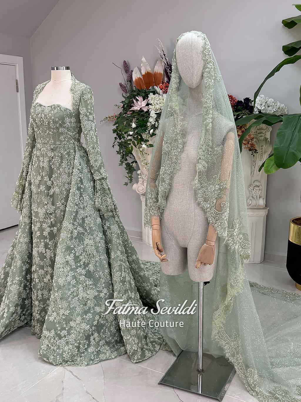 Sage green evening dress with beaded floral lace, a sweetheart neckline and long sleeves with flared lace cuffs, displayed on a mannequin.