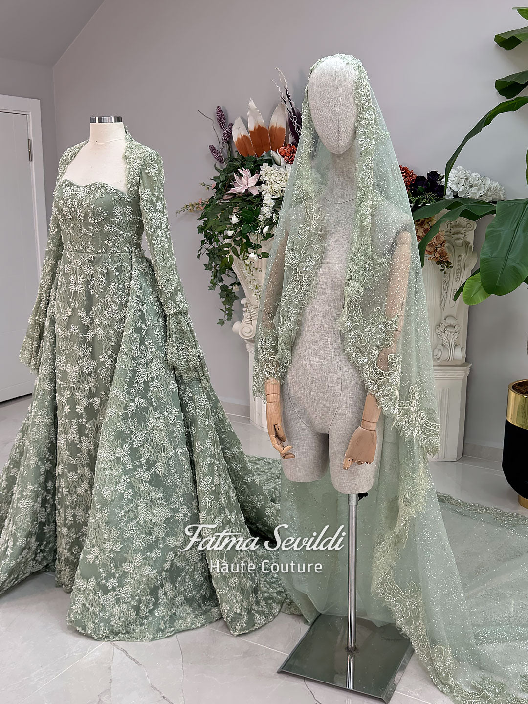 Sage green evening dress with beaded floral lace, a sweetheart neckline and long sleeves with flared lace cuffs, displayed on a mannequin.