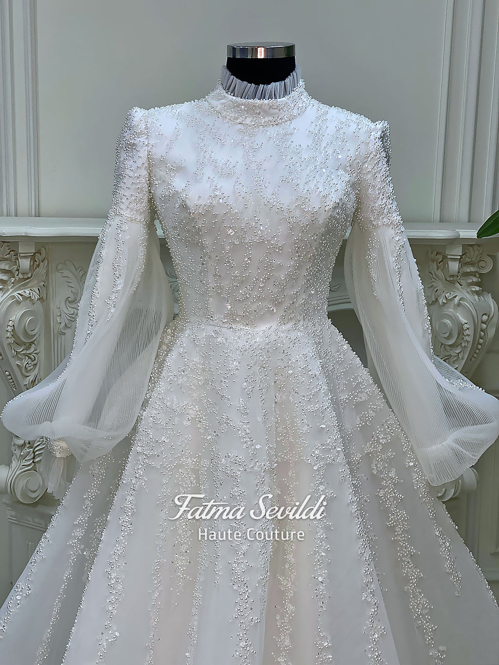 Luxury hijab wedding dress in an A-line tulle ball gown silhouette with long balloon sleeves, high neck, sparkling beadwork, and a lace-edged veil.