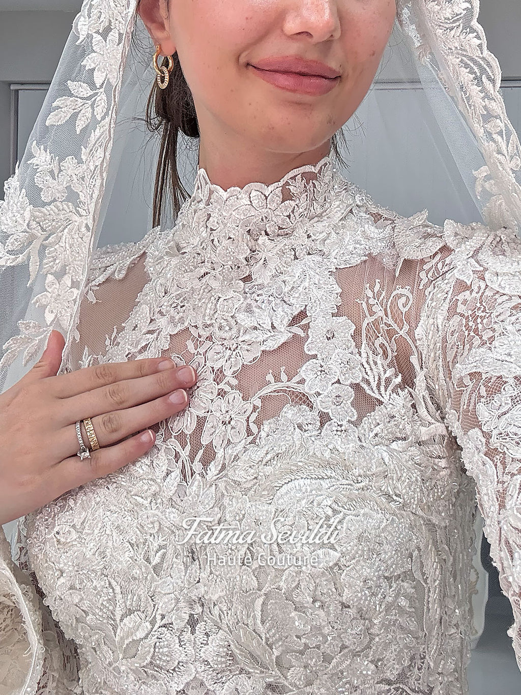Ivory luxury hijab wedding dress featuring long lace sleeves, a high neckline, full beaded floral lace princess skirt, dramatic train and coordinating premium lace veil.