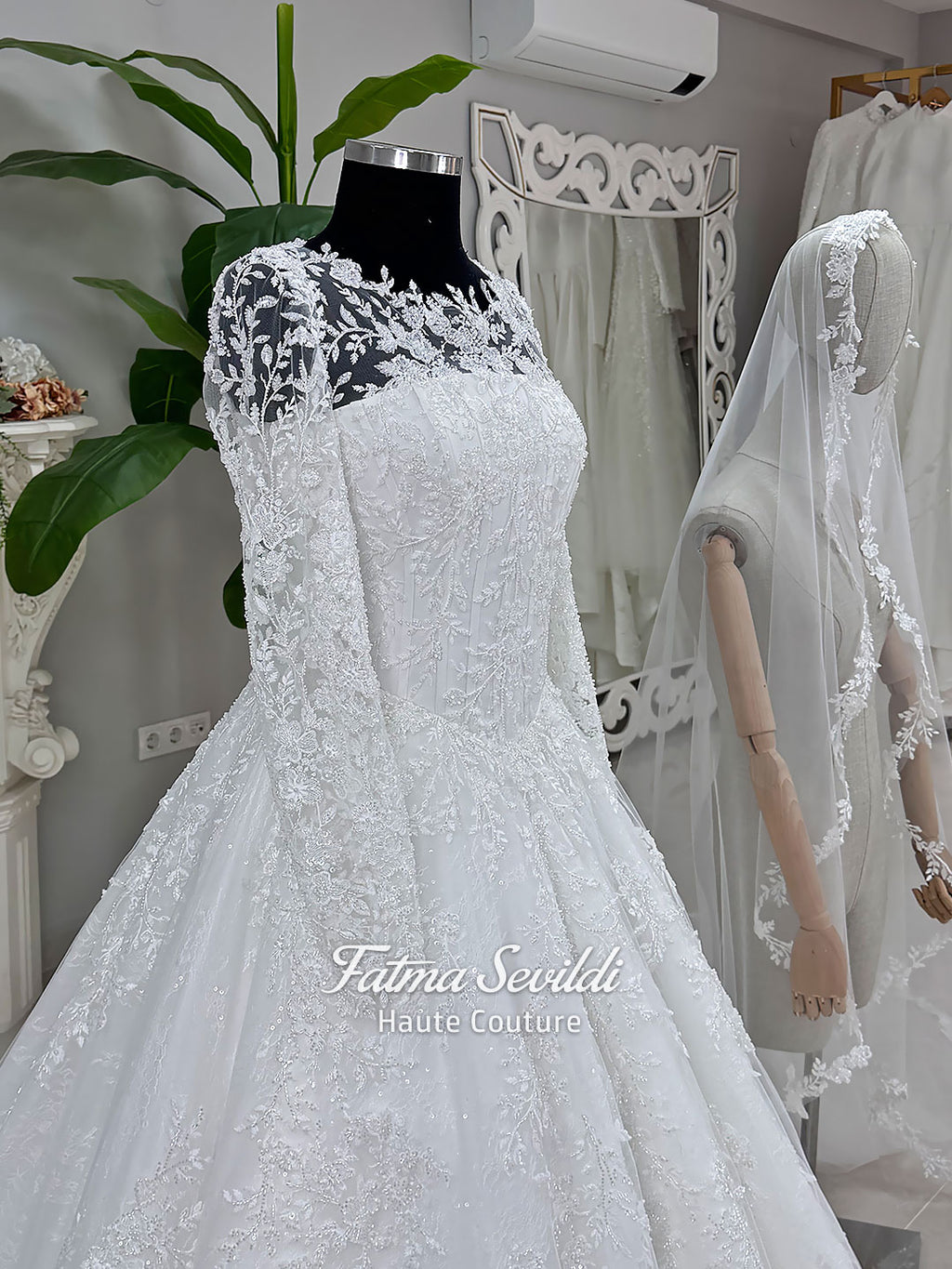 Luxury white hijab wedding dress with long floral lace sleeves, a beaded princess skirt, illusion boat neckline, and a matching premium lace-edged veil.