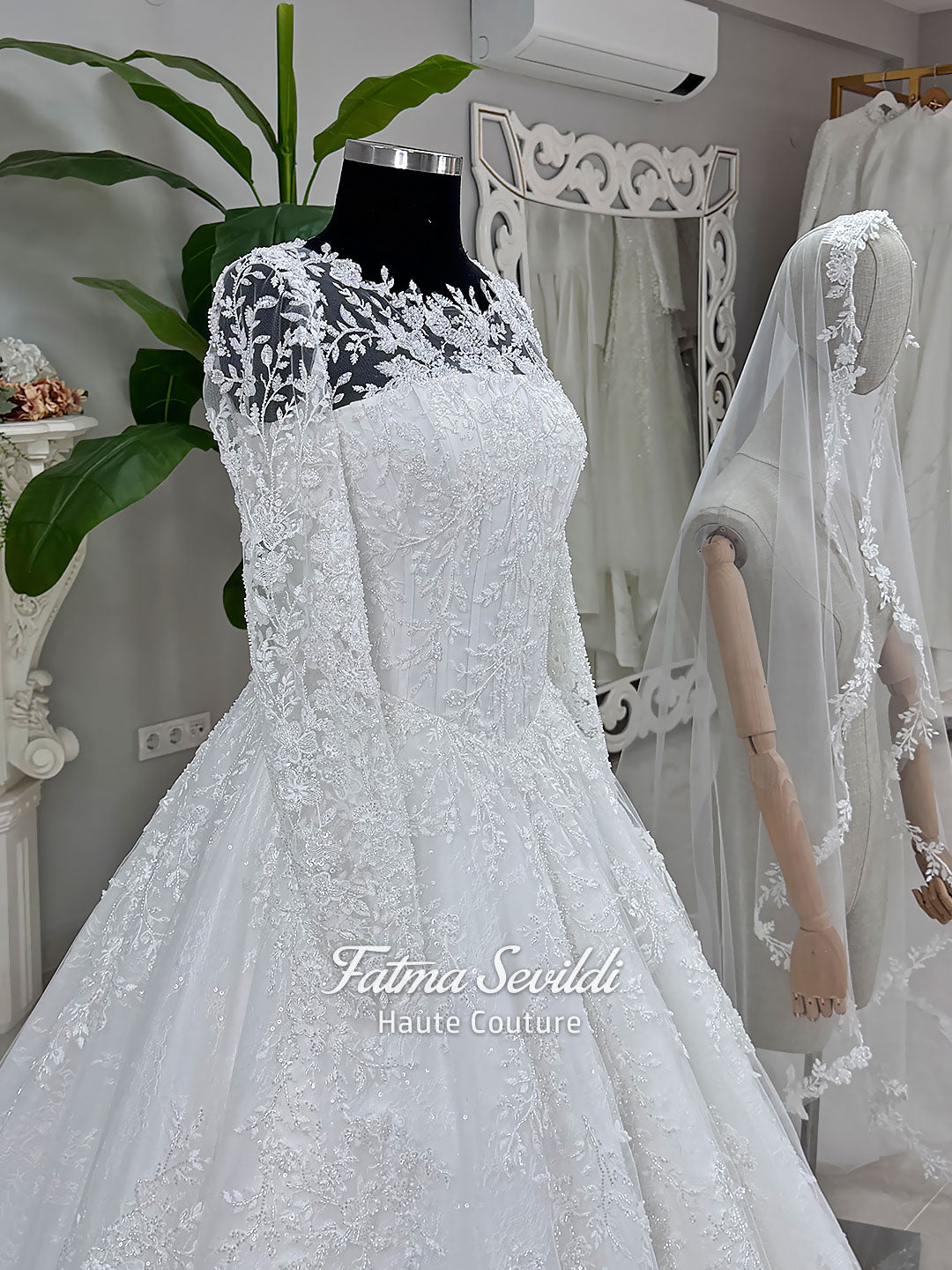 Luxury white hijab wedding dress with long floral lace sleeves, a beaded princess skirt, illusion boat neckline, and a matching premium lace-edged veil.