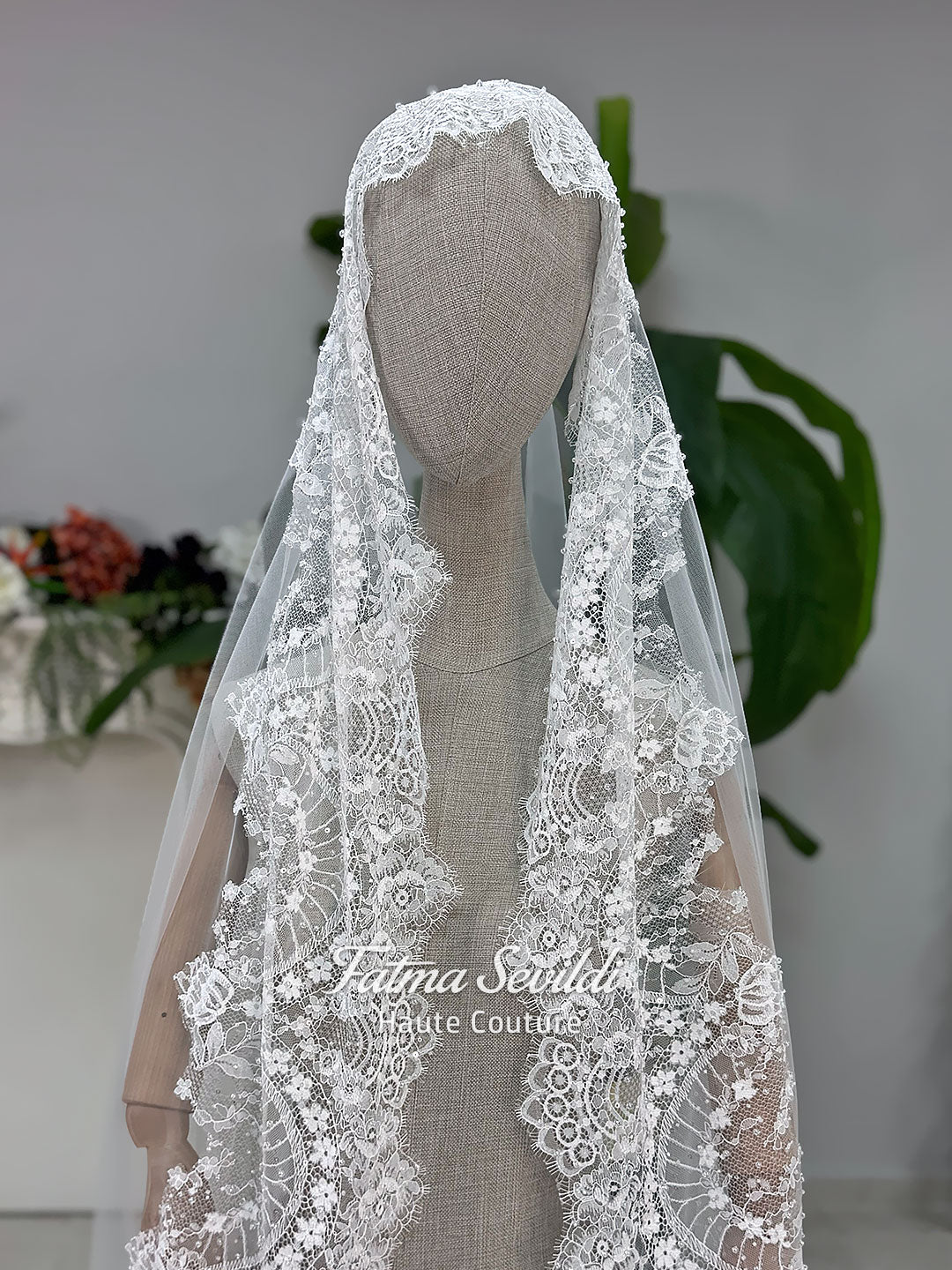Off-white hijab wedding dress by Fatma Sevildi with beaded floral lace, a basque waist, long sleeves and a high neckline.