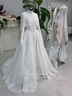 Off-white hijab wedding dress by Fatma Sevildi with beaded floral lace, a basque waist, long sleeves and a high neckline.