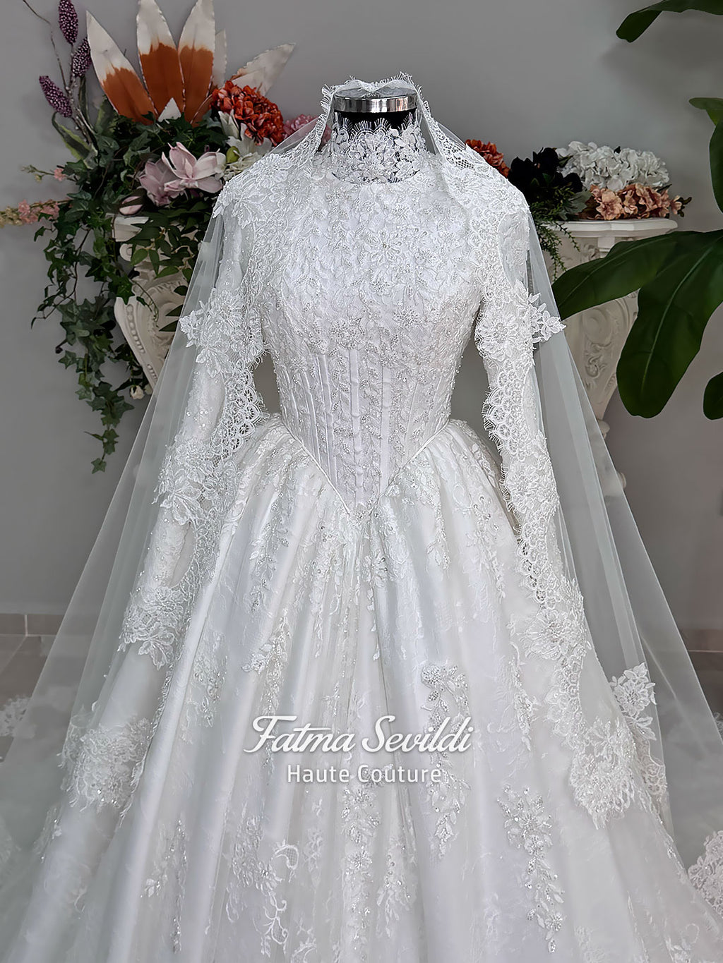 Luxury modest hijab wedding dress ball gown with long sleeves, high neck corset bodice, lace appliqué and included lace veil, photographed in a bridal atelier.