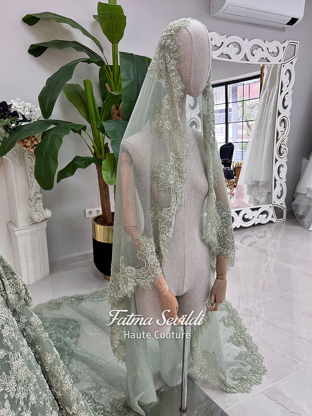 Sage green evening dress with beaded floral lace, a sweetheart neckline and long sleeves with flared lace cuffs, displayed on a mannequin.