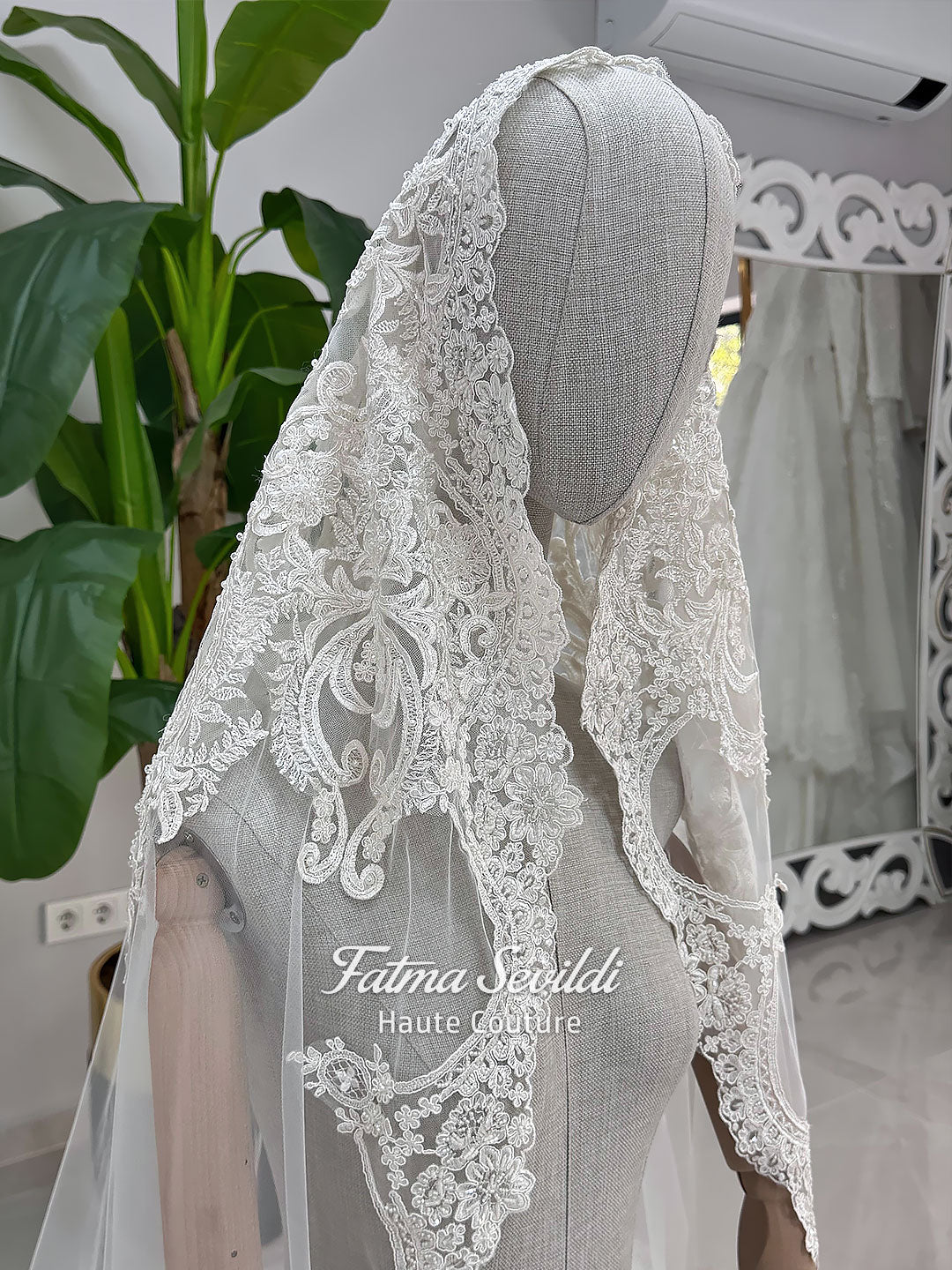 Luxury ivory hijab wedding dress with a high neckline, long sleeves, draped satin skirt and included premium lace veil displayed in a bridal atelier.