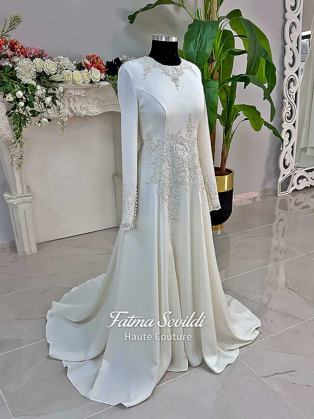 Ivory long sleeve hijab wedding dress with detachable lace-edged cape, floral beaded embroidery, high neckline and floor-length A-line modest bridal silhouette. Designed for Muslim brides seeking an elegant luxury wedding gown with full coverage.