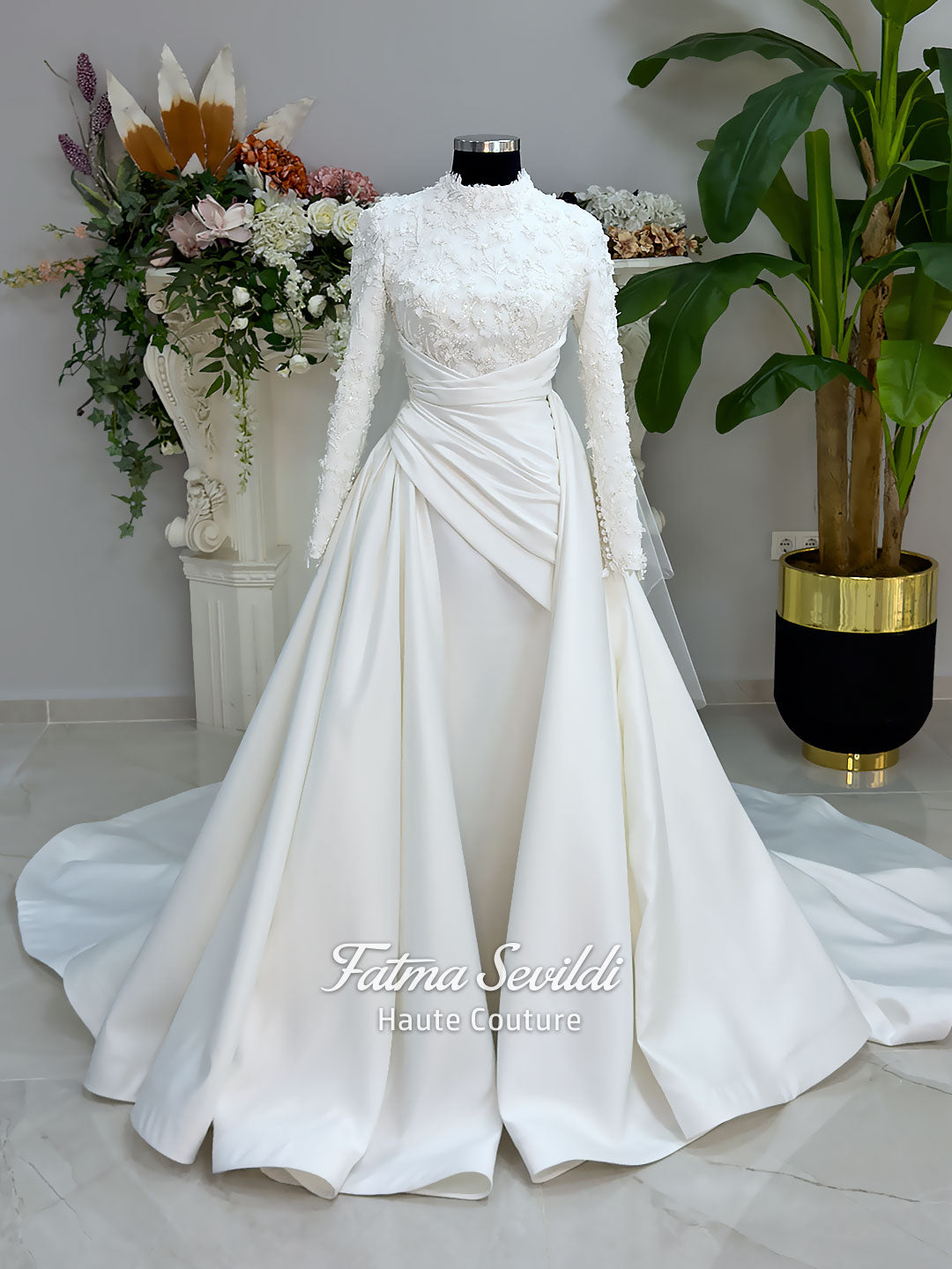 Luxury modest hijab wedding dress with long sleeves, 3D floral beaded lace bodice, draped satin A-line skirt and lace-edged veil included, shown on mannequin. Custom made Islamic bridal gown with elegant full coverage.