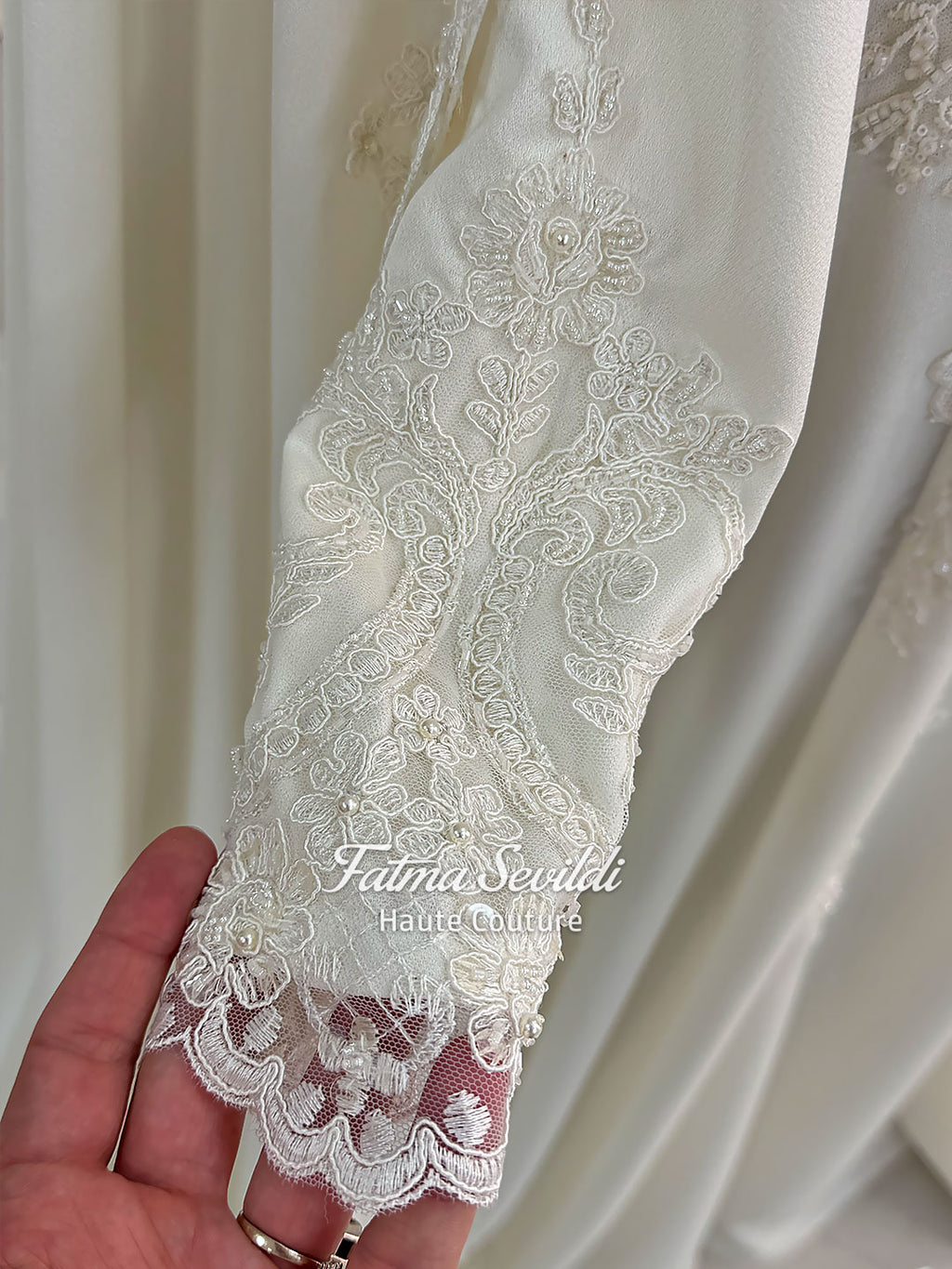 Ivory long sleeve hijab wedding dress with detachable lace-edged cape, floral beaded embroidery, high neckline and floor-length A-line modest bridal silhouette. Designed for Muslim brides seeking an elegant luxury wedding gown with full coverage.