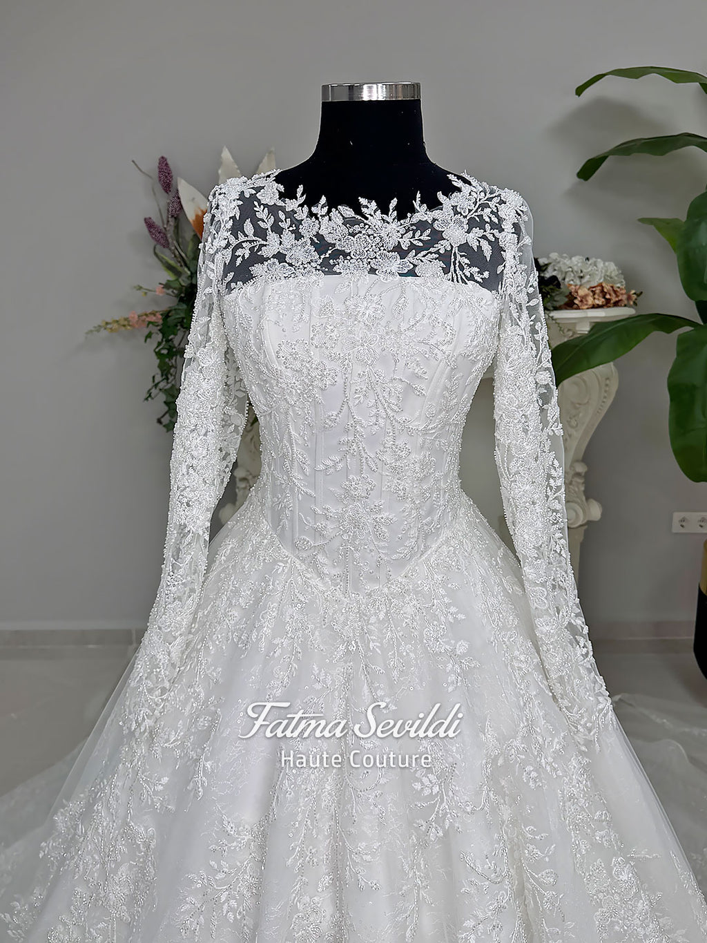 Luxury white hijab wedding dress with long floral lace sleeves, a beaded princess skirt, illusion boat neckline, and a matching premium lace-edged veil.