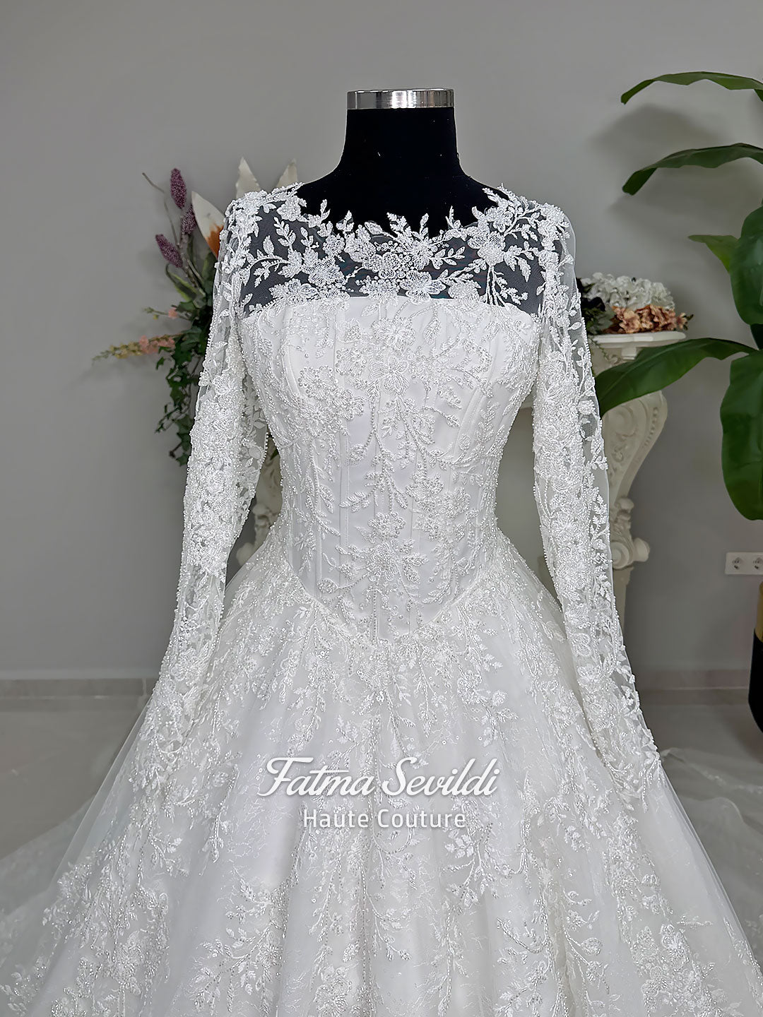 Luxury white hijab wedding dress with long floral lace sleeves, a beaded princess skirt, illusion boat neckline, and a matching premium lace-edged veil.