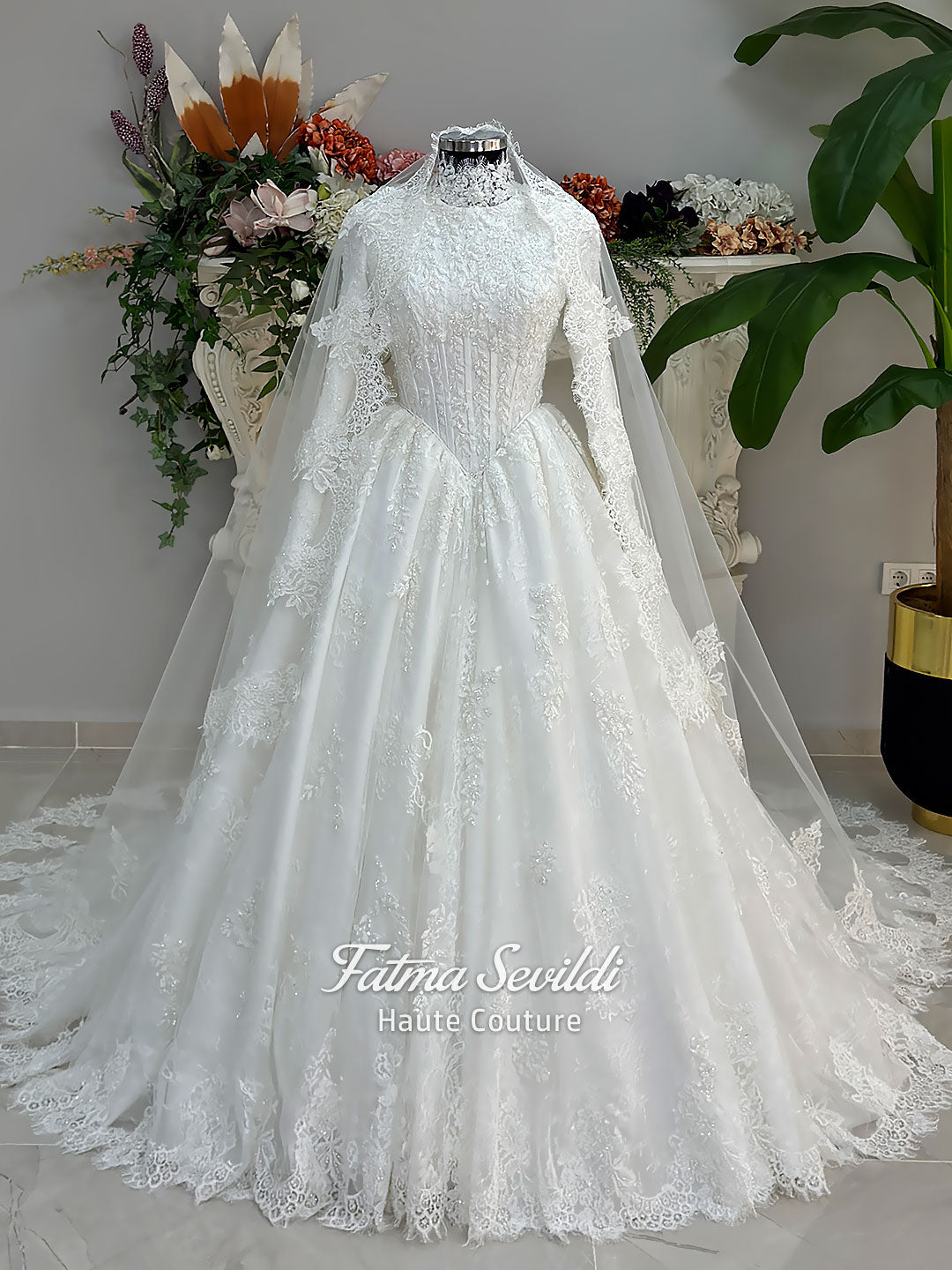 Luxury modest hijab wedding dress ball gown with long sleeves, high neck corset bodice, lace appliqué and included lace veil, photographed in a bridal atelier.