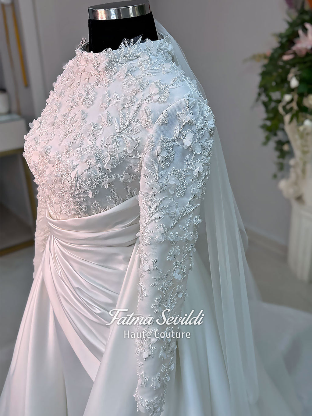 Luxury modest hijab wedding dress with long sleeves, 3D floral beaded lace bodice, draped satin A-line skirt and lace-edged veil included, shown on mannequin. Custom made Islamic bridal gown with elegant full coverage.