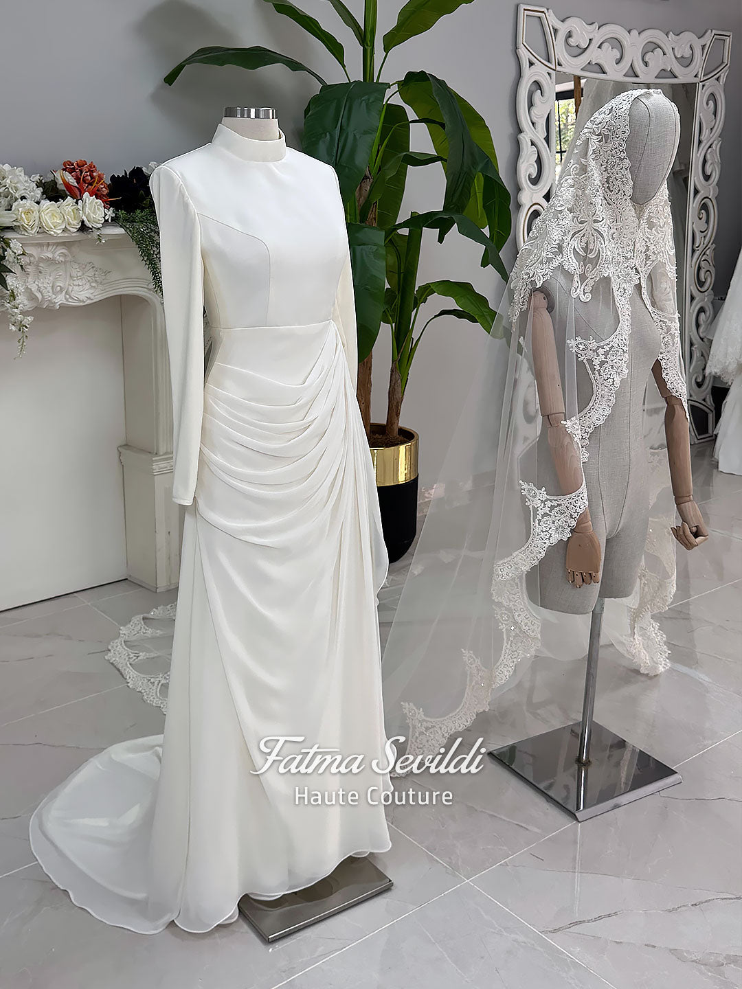 Luxury ivory hijab wedding dress with a high neckline, long sleeves, draped satin skirt and included premium lace veil displayed in a bridal atelier.