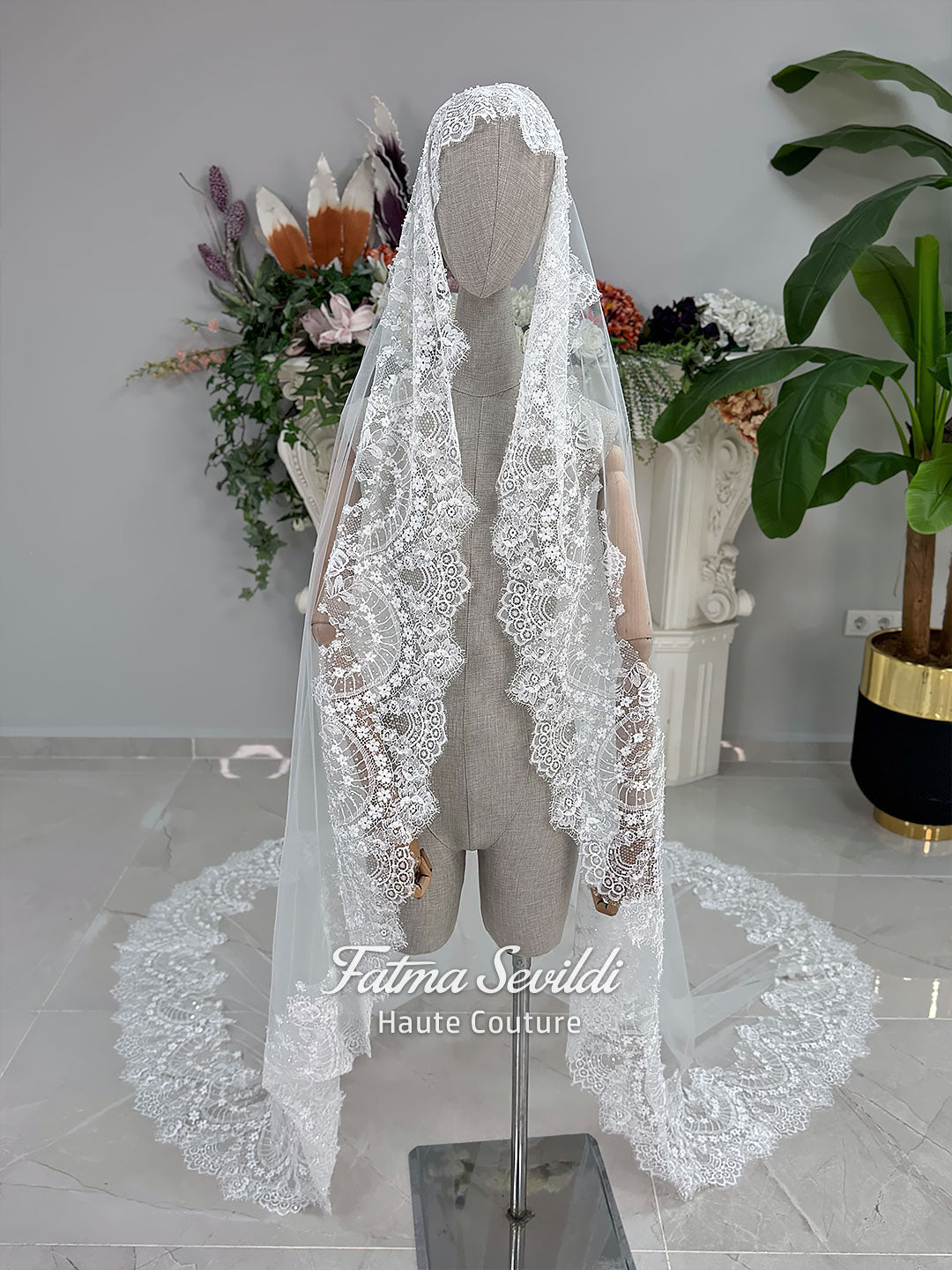 Off-white hijab wedding dress by Fatma Sevildi with beaded floral lace, a basque waist, long sleeves and a high neckline.