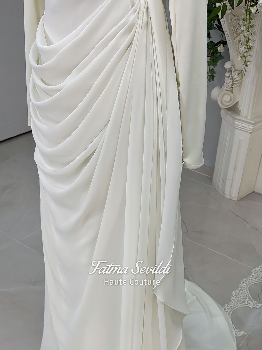 Luxury ivory hijab wedding dress with a high neckline, long sleeves, draped satin skirt and included premium lace veil displayed in a bridal atelier.