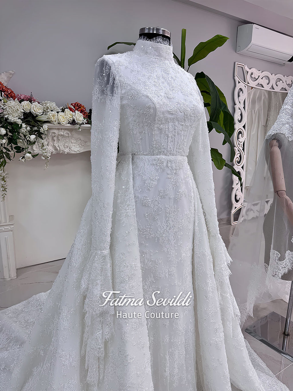 Luxury hijab wedding dress with long flounce sleeves, a high mock neckline, beaded floral lace, corset fit, mermaid silhouette, detachable overskirt, and included lace veil. Modest Muslim bridal gown shown from front, back, and detail views.