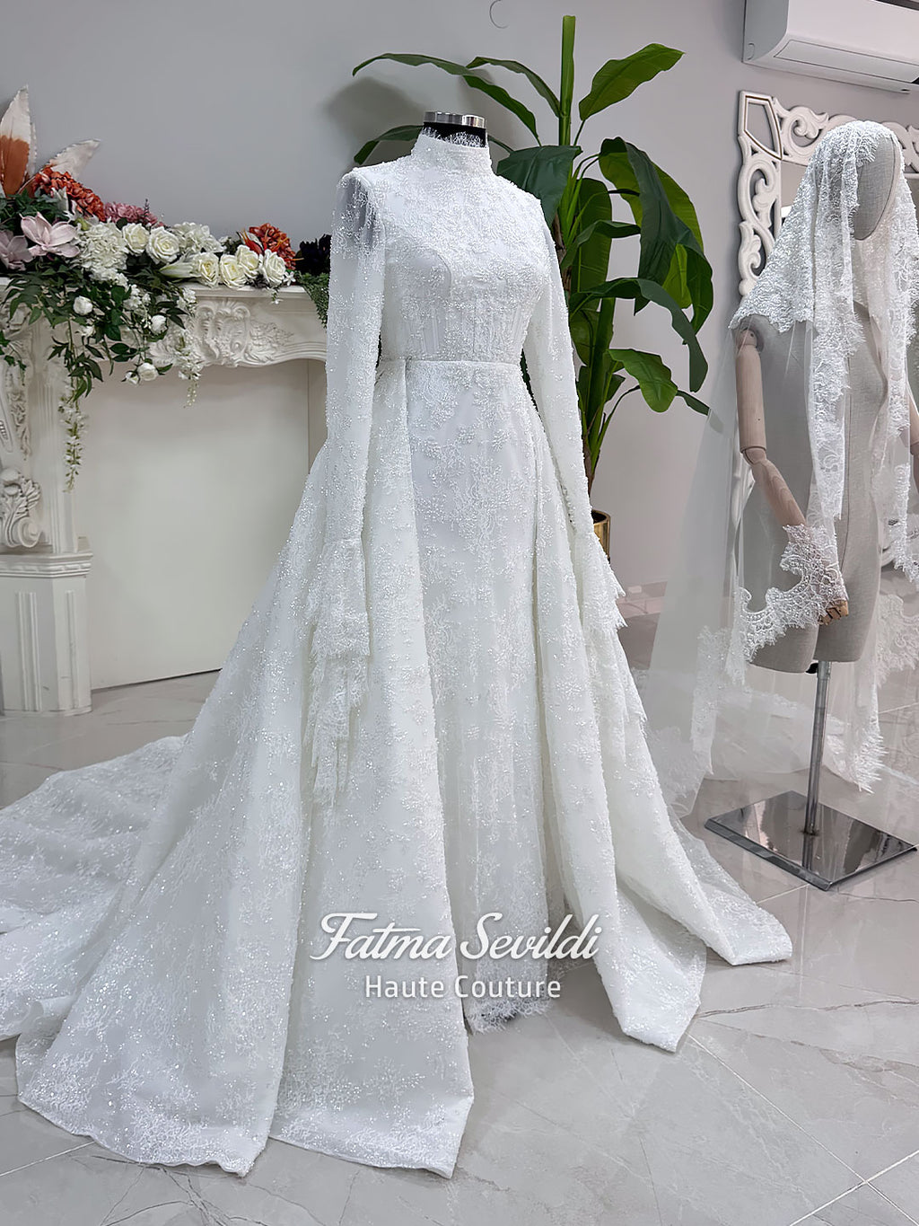 Luxury hijab wedding dress with long flounce sleeves, a high mock neckline, beaded floral lace, corset fit, mermaid silhouette, detachable overskirt, and included lace veil. Modest Muslim bridal gown shown from front, back, and detail views.