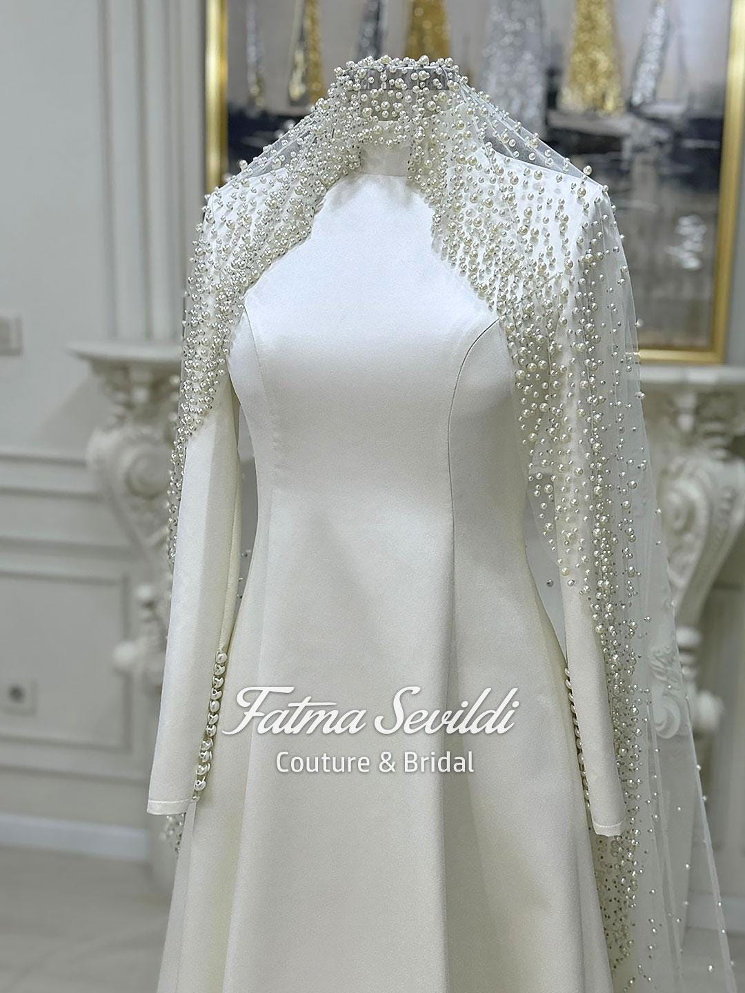Elegant ivory satin A-line bridal gown with long sleeves and beaded veil capelet