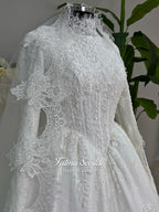 Luxury modest hijab wedding dress ball gown with long sleeves, high neck corset bodice, lace appliqué and included lace veil, photographed in a bridal atelier.